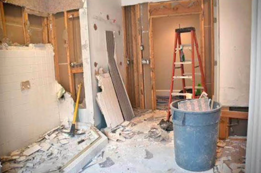 Kitchen and bathroom walls demolished with debris collected in a bin
