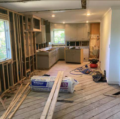Kitchen partially demolished with cabinets removed and subfloor exposed