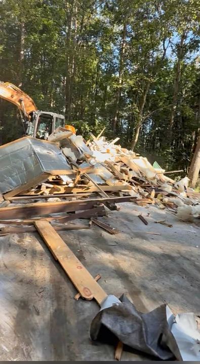 Excavator loading demolition debris and lumber for haul-away on a cleared site