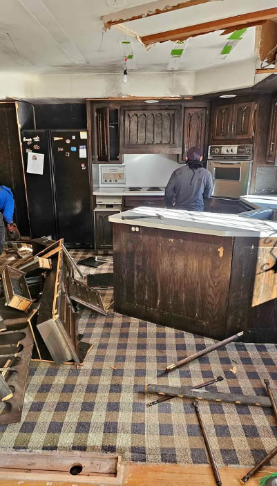 Crew removing dark wood kitchen cabinets and countertops during a kitchen demolition