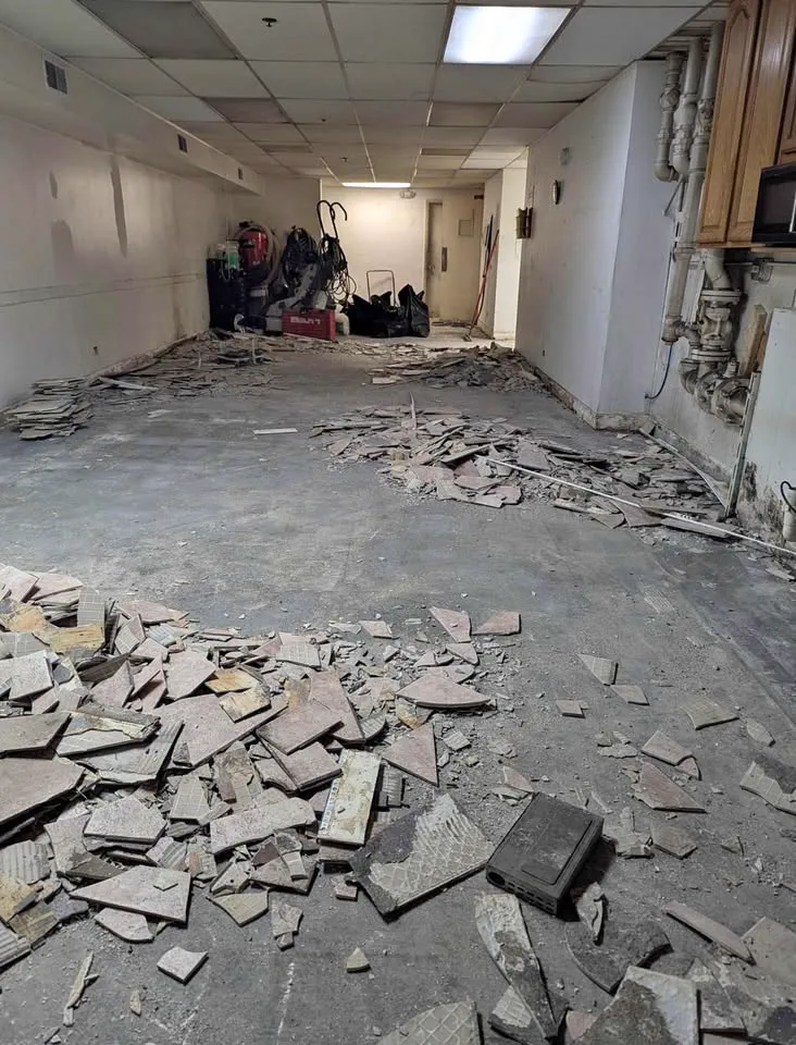 Commercial office corridor with floor tile broken up and piled for removal