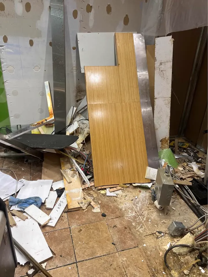 Commercial room with wall panels and counters removed and debris across the floor