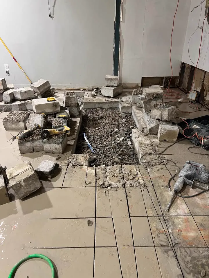 Indoor slab saw-cut into a grid with cut blocks lifted and stacked beside the opening