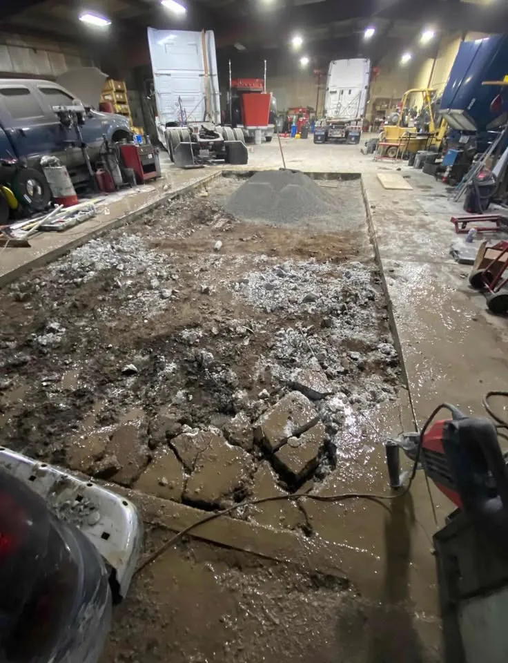 Industrial shop floor with a long strip of concrete slab broken out down to the base