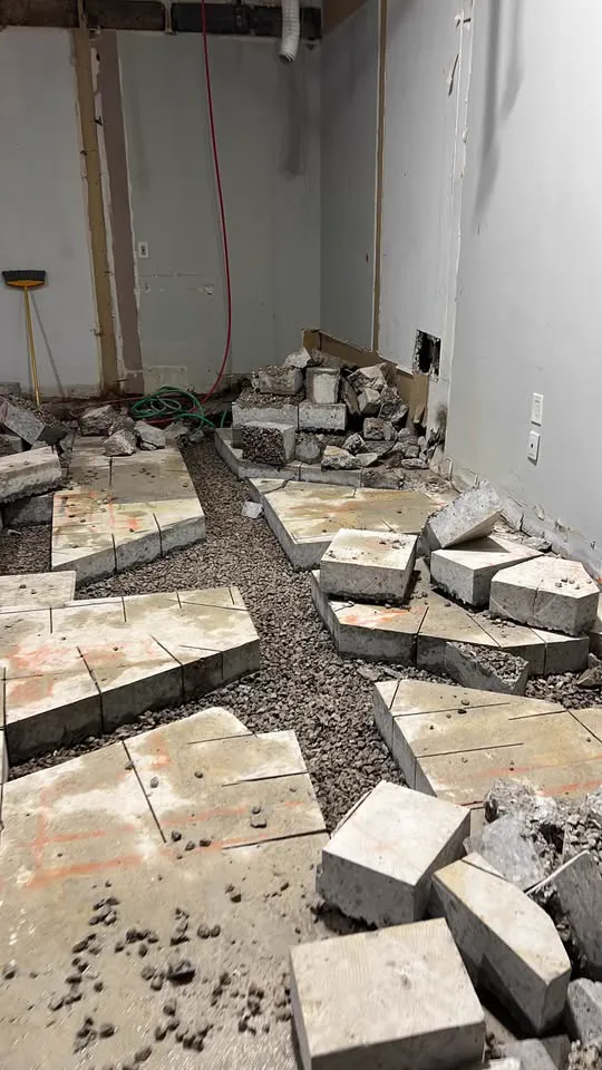 Indoor concrete slab broken into blocks along a trench beside a stripped wall