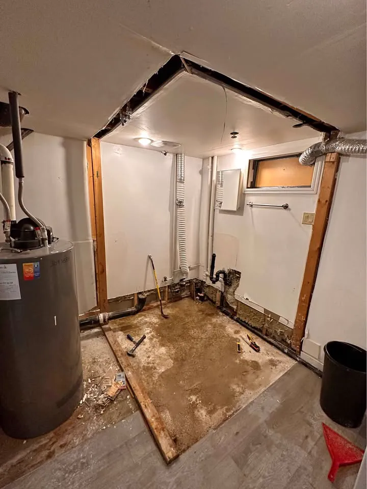 Basement utility room with a wall panel cut away around the water heater area