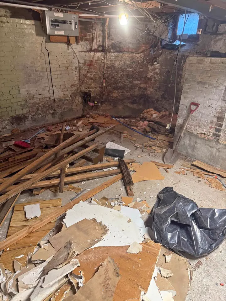 Basement with old brick walls and wood flooring torn up into piles