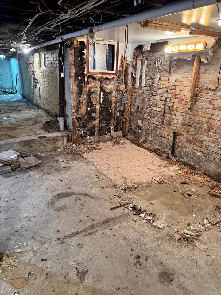 Basement with walls opened back to brick and wiring and the floor bare