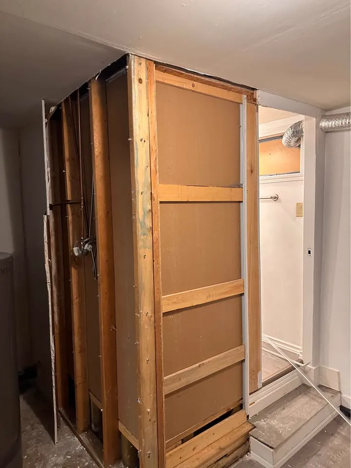 Framed bathroom enclosure stripped to the studs beside a doorway