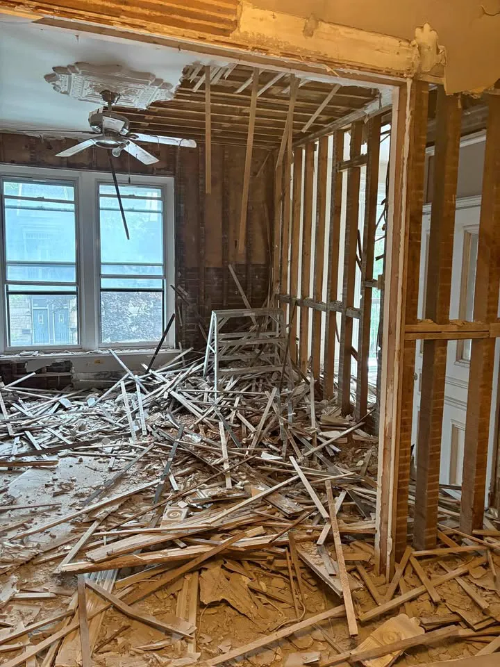 Main-floor room with plaster and lath pulled down to the studs and debris on the floor
