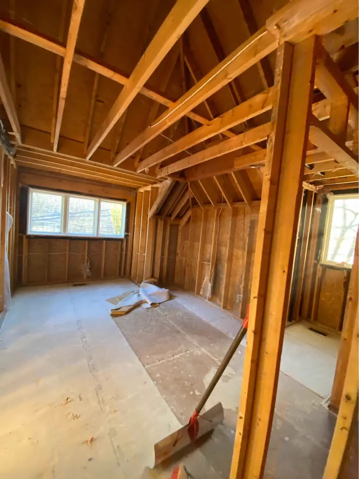 Upper-floor room stripped to the rafters with a broom on the subfloor