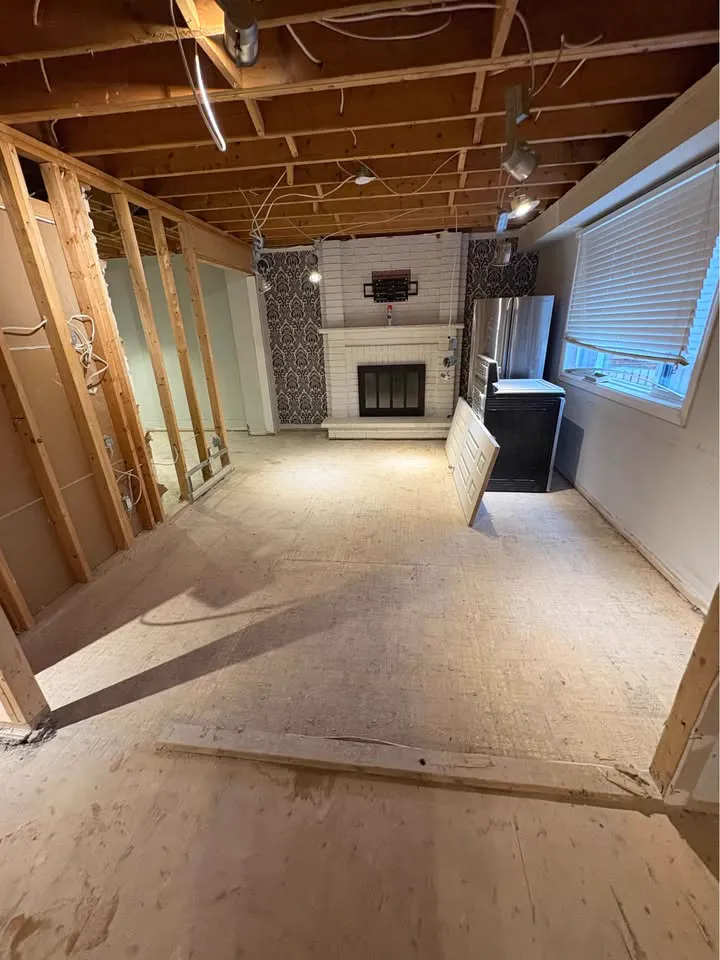 Long room with the ceiling opened to joists and floor cleared, fireplace at the far end