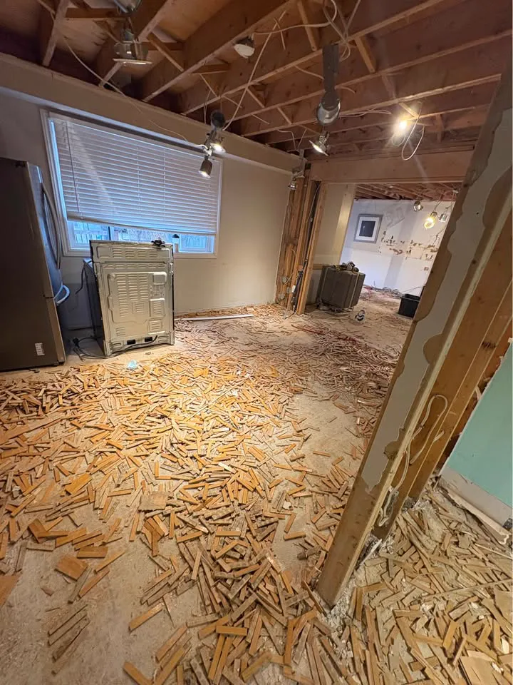 Parquet floor pulled up across a room with the ceiling open to the joists