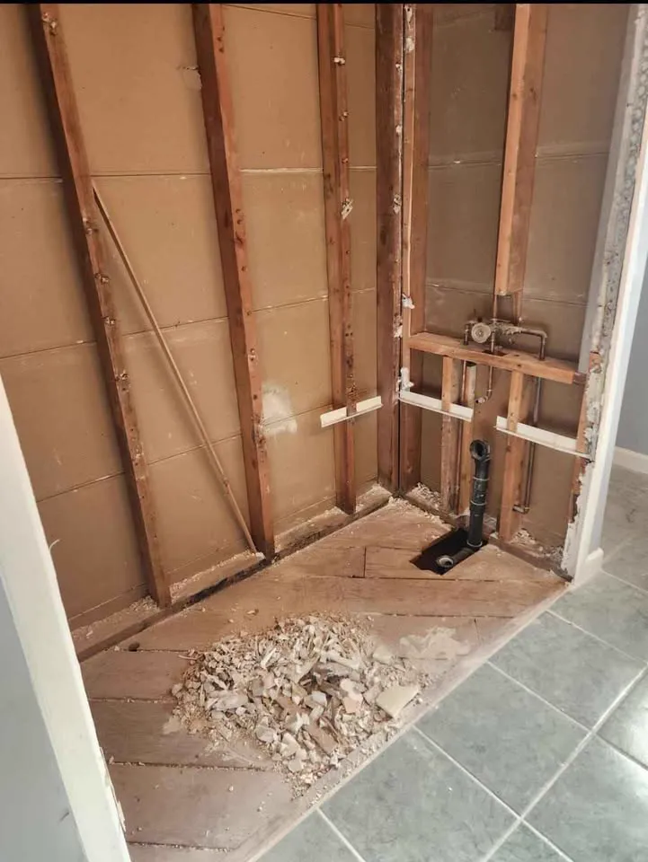 Corner stripped to the studs with a plumbing stub and tile floor exposed