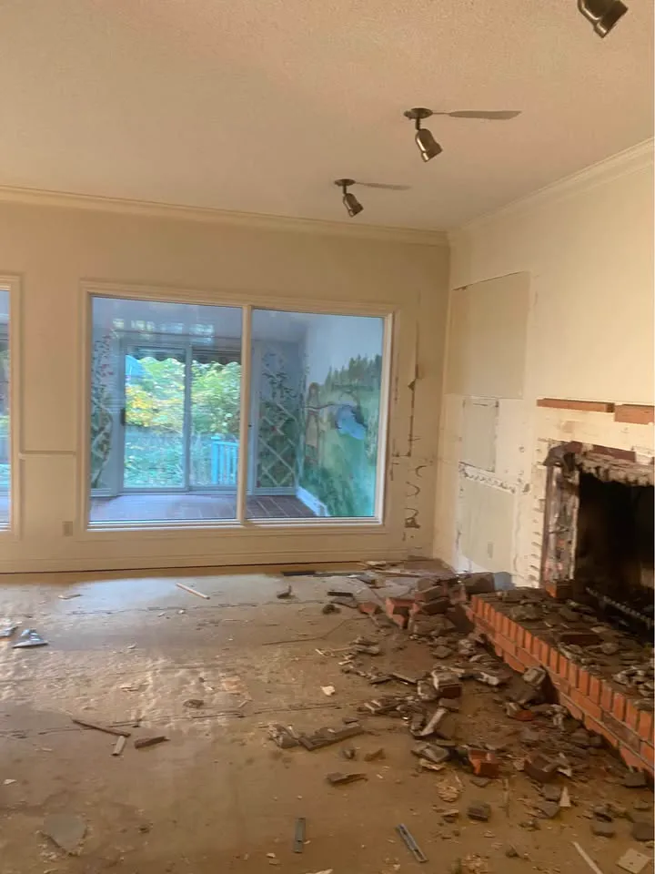 Living room with fireplace masonry being broken out and debris at the hearth