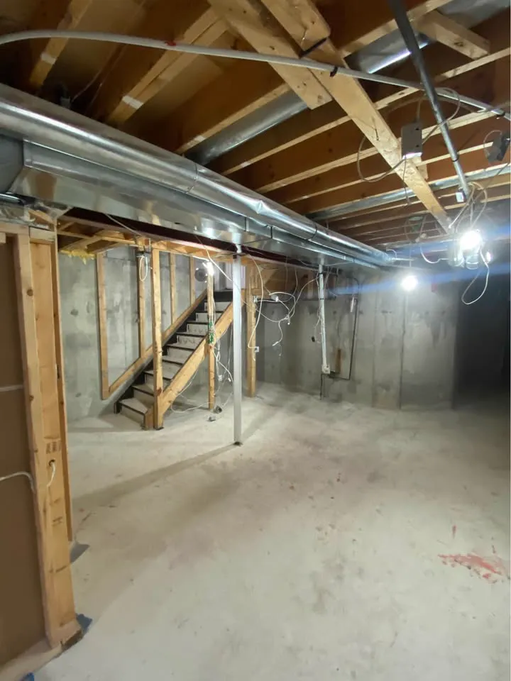 Bare basement with ductwork and ceiling joists exposed and the floor cleared