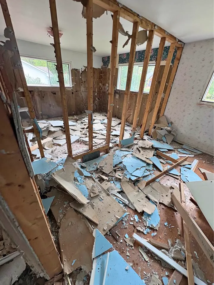 Walls removed to the studs with plaster debris on the floor