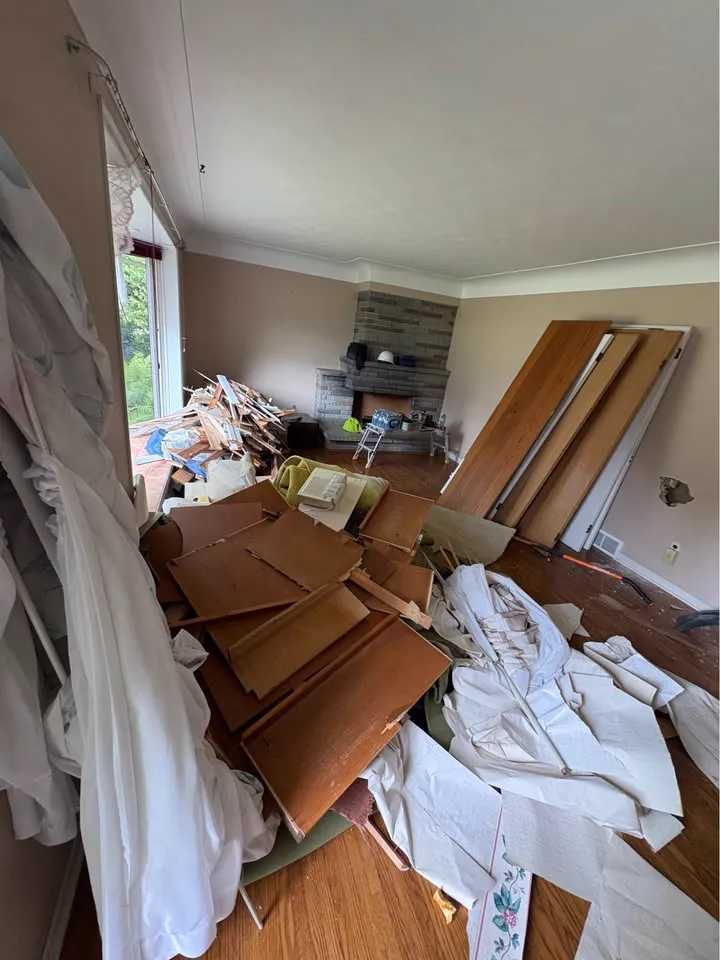 Living room with the ceiling removed and debris and cabinets piled