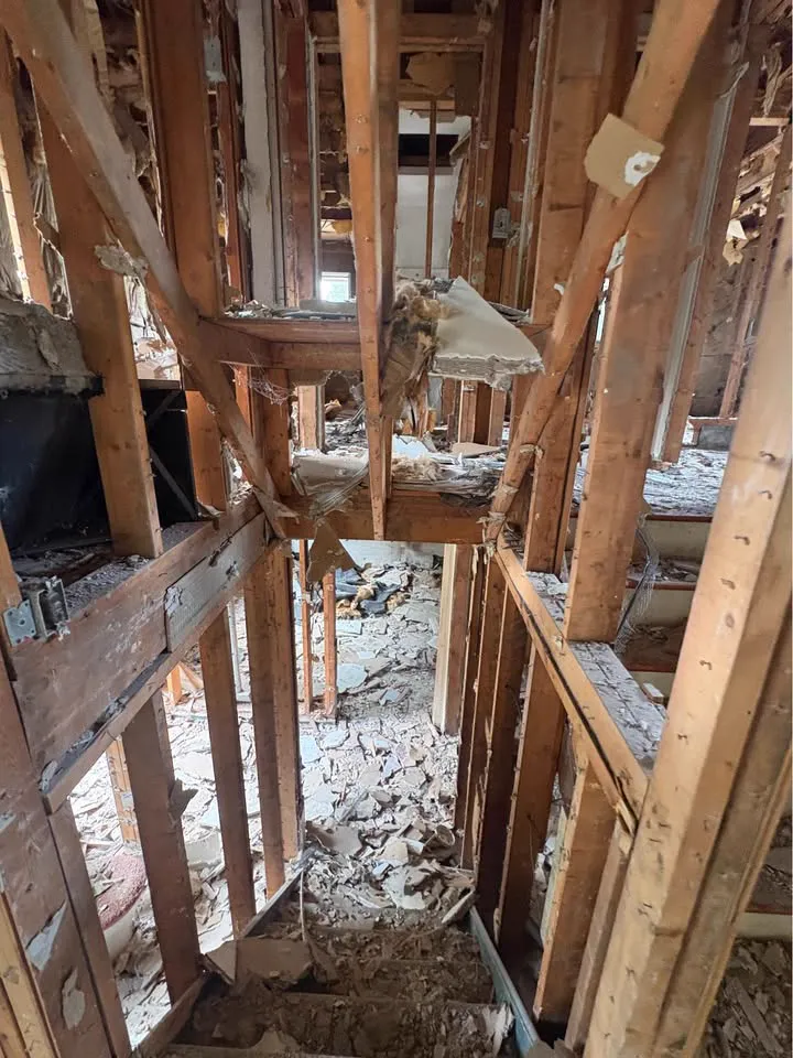 Room gutted to framing with debris between the studs