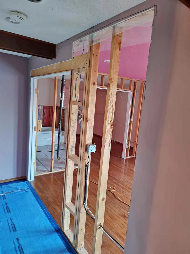 Selective wall opening with studs exposed and hardwood protected by blue film